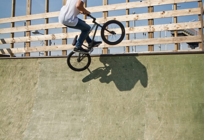 As the bike comes up to the top of the ramp, start leaning the bike in towards the coping. Keep the front end up though. Lean the bike in so the rear peg touches down and your weight stays over the transition.