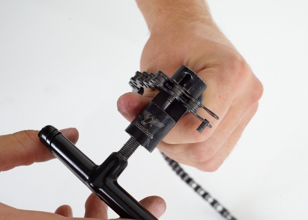 Tighten up the inner link. Make sure the chain is aligned correctly in the tool. The pin should slide into the other side of the chain without too much force. Turn the tool slowly until the pin appears the other side so it’s evenly through the chain.