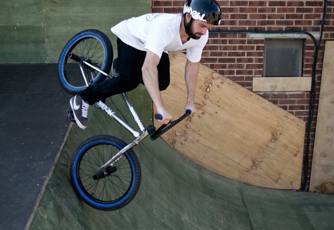As your front wheel goes over the edge, push down with your arms, forcing the bike down into the quarter.